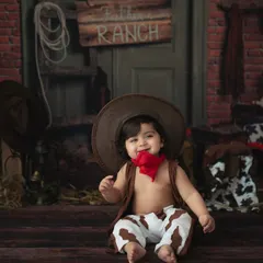 Howdy, partner! This little cowboy is ready for adventure in our rustic ranch-themed setup. The oversized hat and cow-print pants add to the adorable charm.