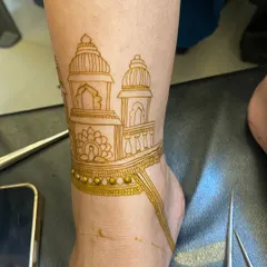 This is the 'before' shot, showing the fresh, natural henna paste for an architectural foot design. You can see the clean lines of the temple domes and the delicate beaded anklet detail.