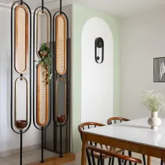 To create a dedicated puja space in the dining area, I designed this movable partition made of cane, brass, and wood. It separates the space beautifully without blocking light, and includes built-in planters.
