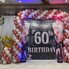 Milestone birthdays deserve a grand celebration. For this 60th birthday, we created an elegant and sophisticated look with a rose gold and white balloon arch, a personalized backdrop, and large foil number balloons to mark the special year.