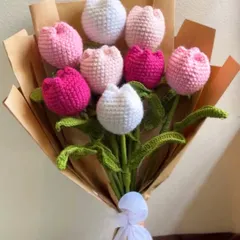 A bouquet that lasts forever. This handcrafted crochet tulip bouquet features a mix of pink, white, and fuchsia tulips, all meticulously stitched and wrapped in brown paper with a delicate white ribbon. It's a timeless gift of love.