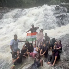 Celebrating the spirit of India with the national flag at the base of a powerful waterfall during a monsoon trek.