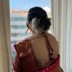 A beautiful view of a classic bridal bun, decorated with delicate baby's breath flowers. This hairstyle is timeless, elegant, and perfect for securing a dupatta or shela.
