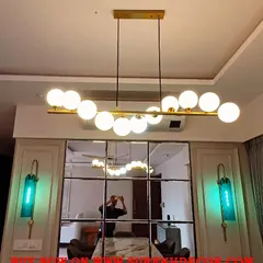 A modern 11 ball chandelier in a golden finish, installed over a dining table. Its linear design is perfect for rectangular tables, providing even illumination while making a strong style statement.