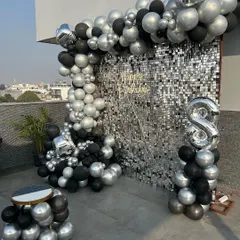 This stunning rooftop setup for a birthday featured a glamorous silver sequin wall, a black and silver balloon arch, and a comfortable, low-seating arrangement under a canopy of fairy lights. It was the perfect blend of chic and cozy for an evening celebration.