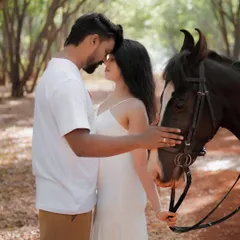 An intimate portrait of a couple with a horse, their foreheads touching in a moment of quiet connection with each other and nature.