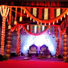 For this wedding mandap, I used pillars decorated with stacked golden pots alongside columns of marigold flowers. The canopy features orange, white, and dark green garlands for a vibrant look.