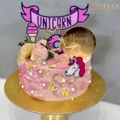A magical unicorn-themed cake for a happy celebration. This pink cake is decorated with gold leaf, sprinkles, and a variety of fun unicorn and ice cream toppers, bringing a bit of wonder to the party.