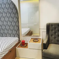 A smart, space-saving design that combines a side table and a dressing table. This custom unit features handle-less drawers and a movable top section, providing flexible functionality without cluttering the bedroom.