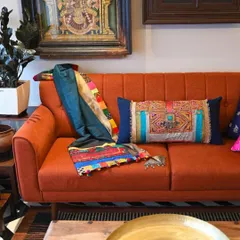 The full view of the Banjara throw and lumbar set on an orange sofa. This combination shows how we can create custom, coordinated textile accents to match your existing decor.