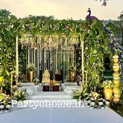 Here is a front-facing view of our grand peacock-themed mandap. The structure is covered in greenery and flowers, with hanging floral strings and chandeliers creating a magical effect, all centered around the ornate couple's seating.