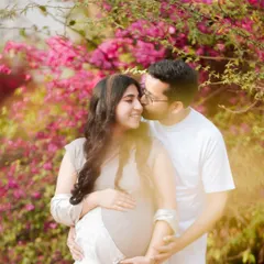 A romantic couple portrait set against a backdrop of vibrant bougainvillea. This outdoor pregnancy shoot highlights the beauty of nature and the couple's bond.