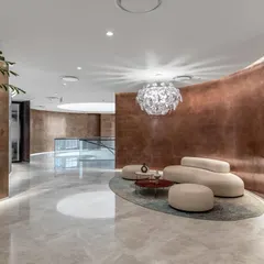 The executive lounge at the Asian Paints headquarters, featuring curved copper-toned walls and plush, modern furniture. This space is designed to be a sophisticated and comfortable area for high-level meetings and client interactions.
