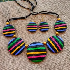 A bold necklace featuring round terracotta pendants with multi-colored stripes. The textured surface adds depth to this modern, graphic piece.