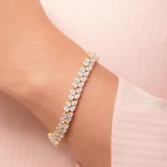 A close-up shot of a sparkling diamond-style bracelet on a model's wrist against a soft pink fabric. This highlights the piece's elegance and shine.