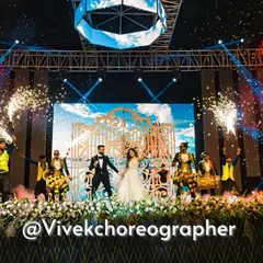 A picture-perfect sangeet entry. This shot captures the scale of our productions, with the couple making their entrance through ornate gates, flanked by dhol players and a stunning display of cold pyrotechnics.