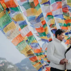 A beautiful portrait of the couple amidst colorful Tibetan prayer flags in Mussoorie. The vibrant flags create a stunning and meaningful backdrop for a romantic photo.