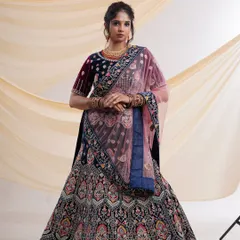 A full-length view of an exquisite navy blue velvet lehenga with intricate multi-color embroidery and a contrasting pink dupatta. This is a perfect rental for a wedding or reception.