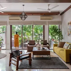 An expansive view showing the open layout and connection to the lush outdoors. The design prioritizes natural light and flow, with carefully chosen furniture like the leather lounge chair adding a touch of timeless style.