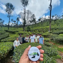 The Rahasya Daari badge held up against a beautiful tea estate. It's a symbol of the unique trails and hidden paths I love to share with my groups.