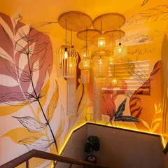 We transformed this restaurant staircase into an immersive art installation. The walls are covered in a warm, yellow-toned mural, and a cluster of bamboo and wicker lights adds a sculptural element.