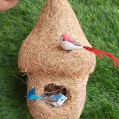A classic, teardrop-shaped coir bird nest. These are eco-friendly, durable, and provide great shelter for birds. The little decorative birds show how cute they look when hung in a garden.