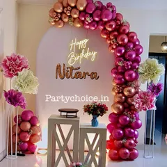 An elegant home birthday decoration featuring a stunning balloon arch in shades of metallic pink and rose gold. We added large paper flowers and a neon "Happy Birthday" sign to complete the look.