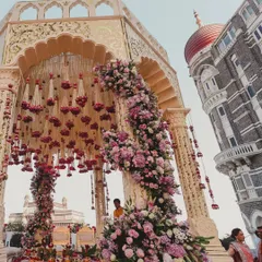 A magnificent mandap set against the iconic dome of the Taj Mahal Palace in Mumbai. The structure is adorned with cascading florals, blending royal architecture with opulent wedding design.