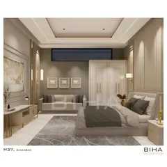 This view of the Ghaziabad master bedroom showcases its generous layout, which includes a comfortable seating area with a sofa. The consistent use of neoclassical wall mouldings and a neutral color scheme unifies the different zones of the room, creating a cohesive and expansive feel.