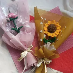 A lovely pairing of two single stem bouquets. On the left is a delicate pink flower, and on the right is our classic sunflower, both beautifully wrapped and ready to gift.