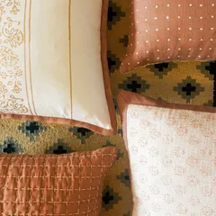 Another arrangement of our handcrafted cushions, resting on a geometric dhurrie. The soft textures, earthy hues, and subtle patterns are designed to bring a sense of sustainable, handcrafted style to any home.