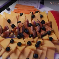 A beautiful cheese platter featuring Gouda, fresh figs, and blueberries. Our tasting selections are curated to offer a journey through the world's finest cheeses.
