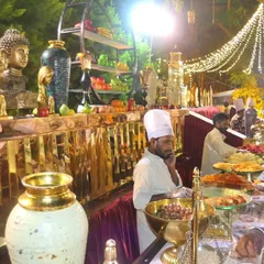 An ornate golden buffet setup for a royal-themed wedding. The decorative vases and Buddha statues add a touch of class and serenity to the dining area.