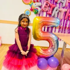 An older sister celebrating her fifth birthday in a beautiful ombre tiered gown that shades from wine to pink. This dress was part of a coordinated set with her younger sister.