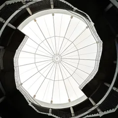 Looking up from the central courtyard of Mount Carmel School, the helical staircases spiral towards the skylight. This feature was designed to resemble a human DNA strand, creating a powerful visual metaphor for growth and connection at the heart of the school.