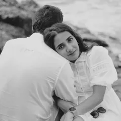 A quiet, soulful moment on the rocks by the sea. This black and white pre-wedding portrait captures a sense of calm intimacy and deep connection, with the ocean as a timeless backdrop.