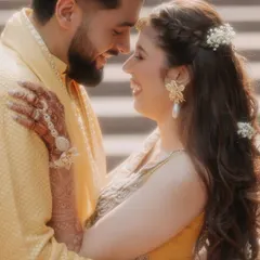 The pure, unscripted joy of a Haldi ceremony. This close-up captures a genuine smile and the beautiful details of the moment, from the floral jewelry to the shared laughter.