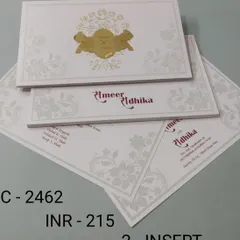 A clean and simple white invitation with a central gold foil emblem. The design includes inserts with a touch of red for the names, adding a pop of color.