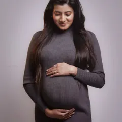 A quiet and tender moment from a maternity shoot. The mother-to-be looking down at her belly, captured with soft, diffused lighting.