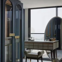 A sleek and modern vanity area for a daughter's bedroom. The blue-grey arched wardrobes with glass doors are paired with a freestanding vanity table and a large oval mirror, creating a chic and functional space.