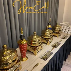 A close-up of our elegant buffet setup, featuring ornate gold chafing dishes and decorative vases against a simple, modern backdrop.