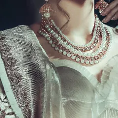 A detailed shot focusing entirely on the multi-layered pearl necklace and the intricate fabric of the saree. This type of image is crucial for highlighting the craftsmanship of couture garments and accessories.