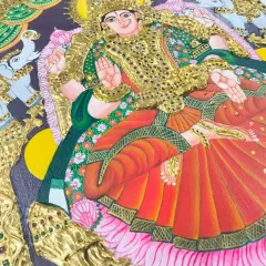 A close-up of a finished Tanjore painting of Goddess Lakshmi, adorned with shimmering stones and 24K gold foil. This piece is a testament to the student's dedication and skill.