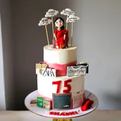 This two-tier cake was designed to celebrate a mother's 75th birthday by telling her life's story. It features a hand-sculpted figurine and edible toppers representing her career as a teacher, her love for shopping, and her journey through life.