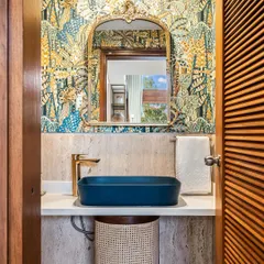 Revitalize your cloakroom with a touch of elegance. Here, captivating wallpaper, a classic mirror, and a bold blue sink create a chic and impactful design.