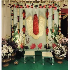An elegant Pellikuthuru decor setup featuring the sacred Tirupati namam made of flowers. The backdrop and floral arrangements are designed to create a divine atmosphere for the bridal ceremony.