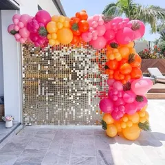 This vibrant balloon arch is perfect for daytime outdoor events like pool parties or brunches. The mix of bright pink, orange, and yellow balloons against a gold shimmer wall creates a fun and tropical feel.