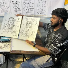 Here I am at my station, showing off a couple of recently finished birthday caricatures. You can see some famous faces I've drawn for practice in the background.