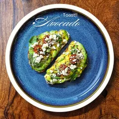 An overhead view of our avocado toast on a beautiful blue plate. The presentation makes it taste even better.