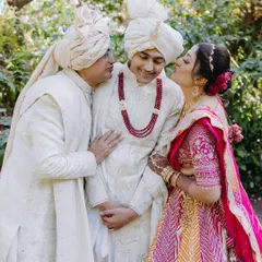 A sweet and candid moment between the groom and his parents, as his mother gives him an affectionate kiss on the cheek.
